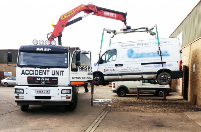 Van being lifted off lorry using crane